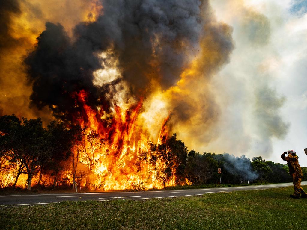 A rural firefighter watches on as the bushfire blazes east of the David Low Way at Peregian Beach last month. Photo Lachie Millard