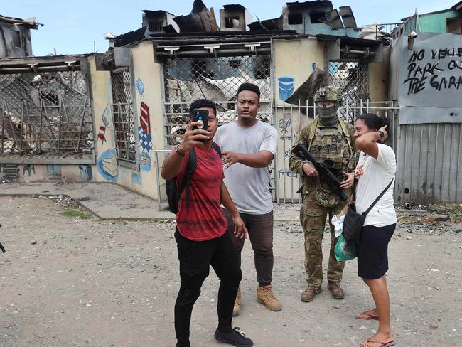 Locals having their photos taken with an Aussie soldier in a burnt out section of Chinatown. Picture: Gary Ramage