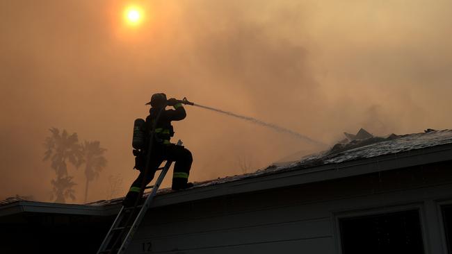 A firefighter sprays water on a burning home at Altadena as the 4000ha Eaton Fire moves through the area. Picture: Getty Images via AFP