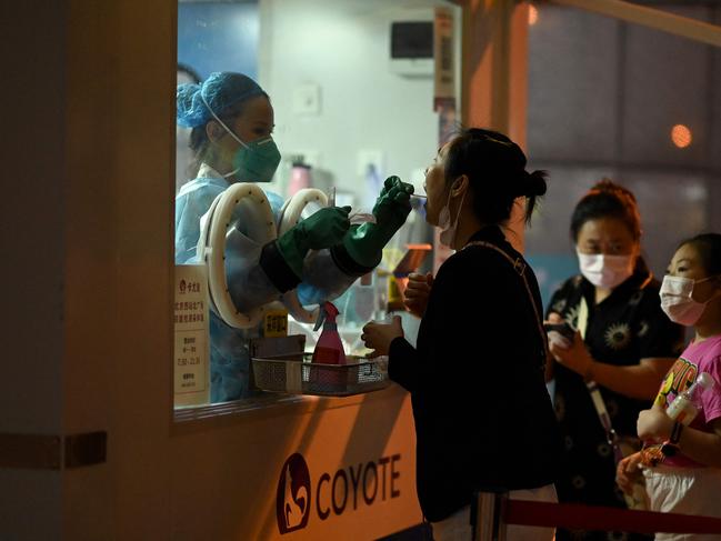 TOPSHOT - A health worker takes a swab sample from a woman to be tested for Covid-19 coronavirus at a nucleic acid sample collection station at the Beijing West railway station in Beijing on August 5, 2021. (Photo by Noel Celis / AFP)