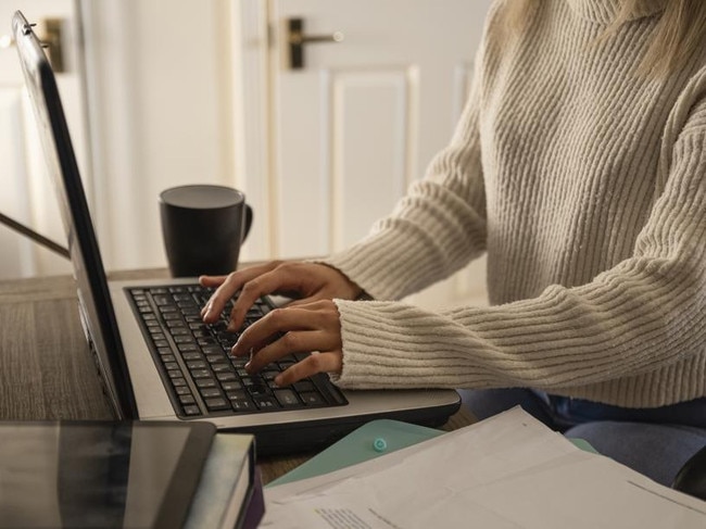 An unrecognisable young woman using her laptop and completing some work at home in Northumberland, North East England.