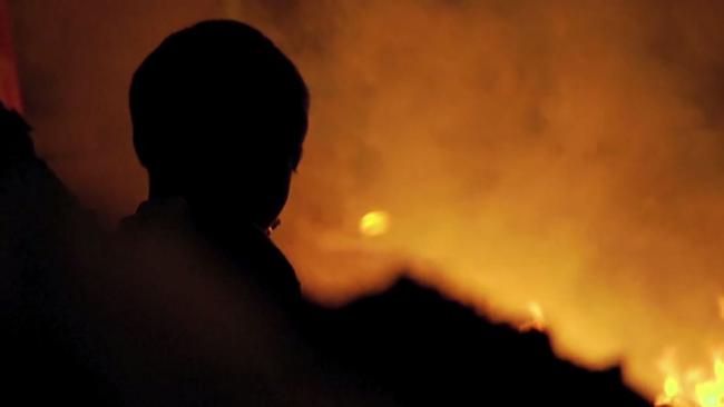 In the Plastic China documentary. waste burns and a child looks on.