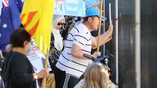 Protesters look through the high fence outside the South Australian Chinese consulate in Adelaide. Picture: NCA NewsWire / David Mariuz