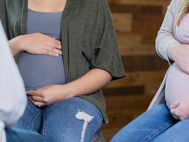 Group of young adult Hispanic and Caucasian pregnant women are meeting for a prenatal support group or childbirth class with midwife or doctor.