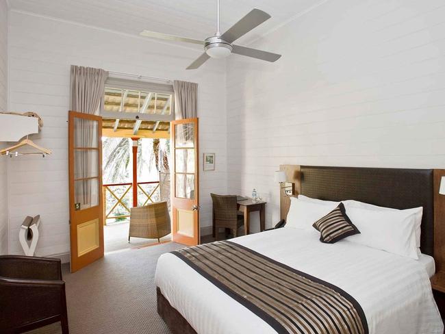 A Heritage room at the Q Station with French-style doors leading onto a furnished balcony with 2 chairs and a coffee table. Picture: Accor.