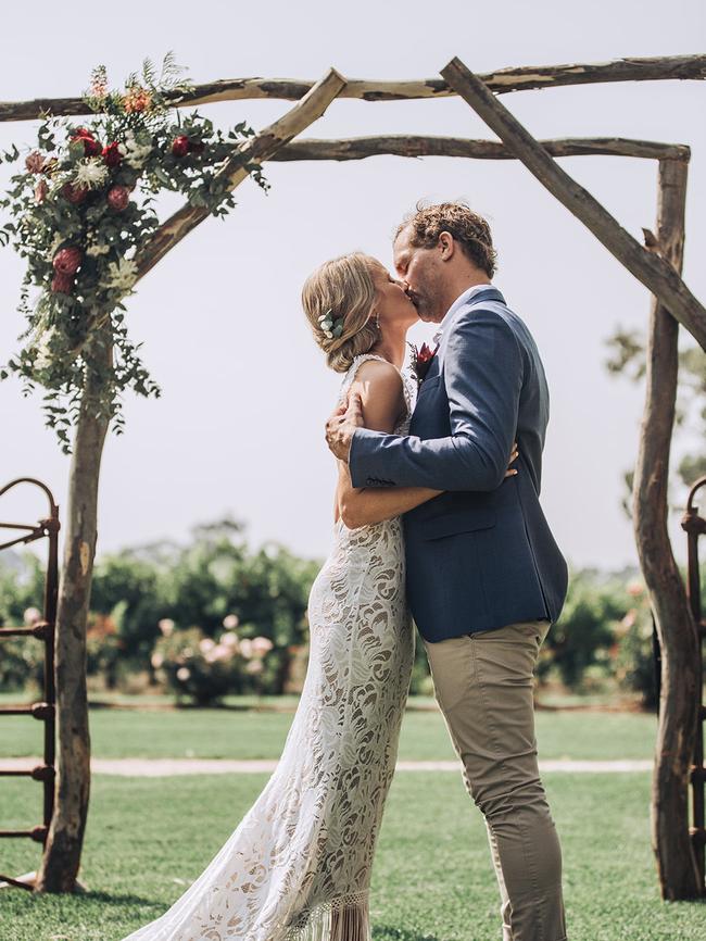 Melanie and Jamie Clapp kiss under their arbour made from farm gates, at Lake Breeze in Langhorne Creek. Photographer: Alysha Sparks