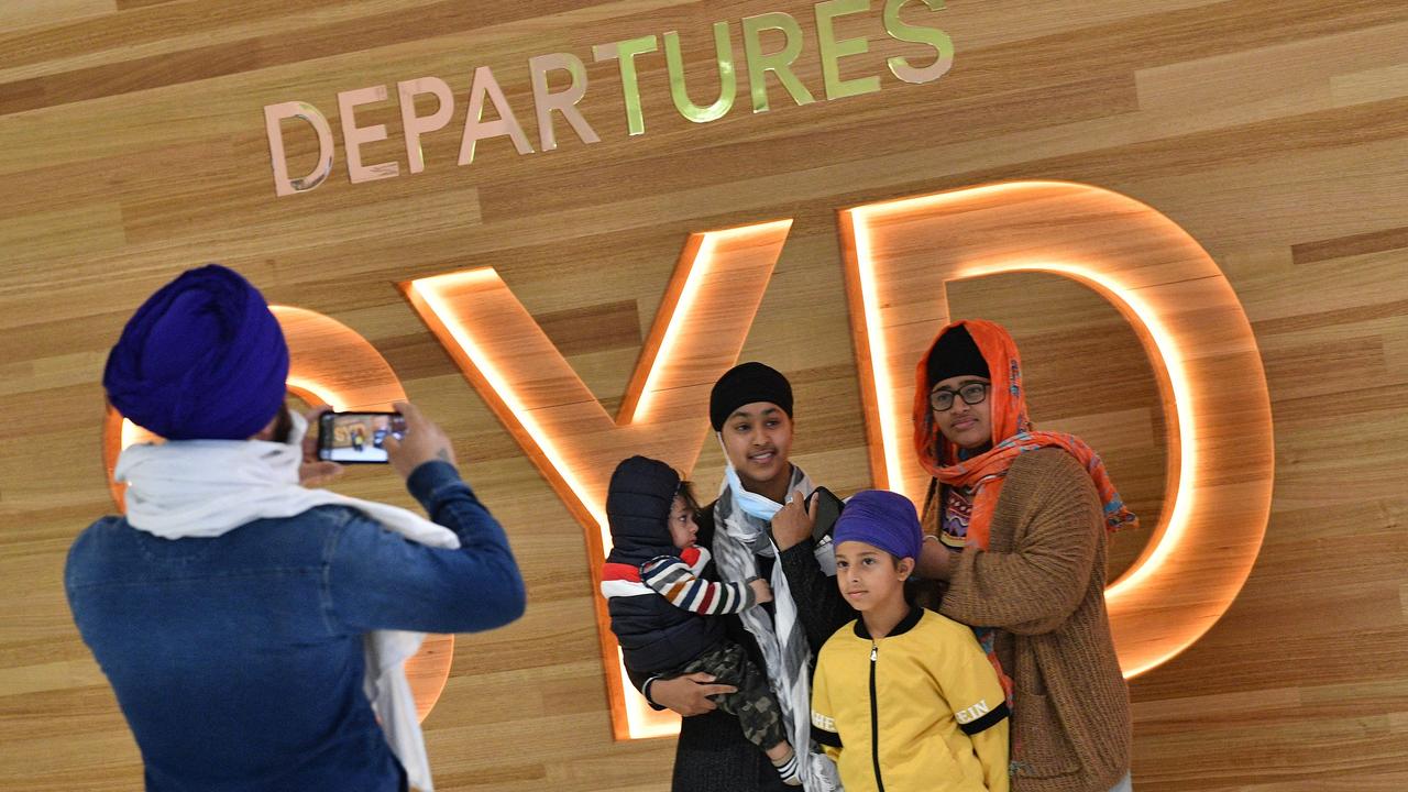 A family takes photos at Sydney International Airport before their flight for New Zealand. Picture: AFP