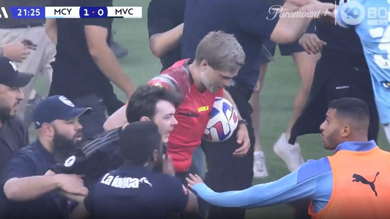 Referee Alex King attempts to leave the ground as security and players try to contain fans who invaded the pitch at AAMI Park. Picture: Fox Sports