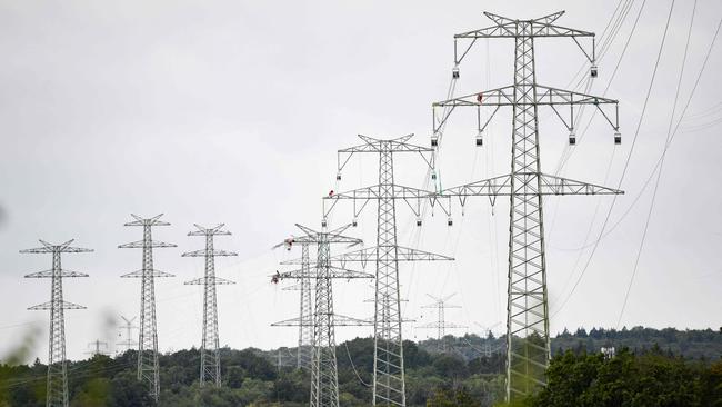 General view taken as workers of electricity transmission operator TransnetBW assemble a 380-KV power line on a high-voltage power pole near Pforzheim, southern Germany, on August 3, 2023. TransnetBW operates the electricity transmission grid in Federal state Baden-Wuerttemberg and expands it with a new 12 kilometers long high-voltage line near this city. (Photo by THOMAS KIENZLE / AFP)