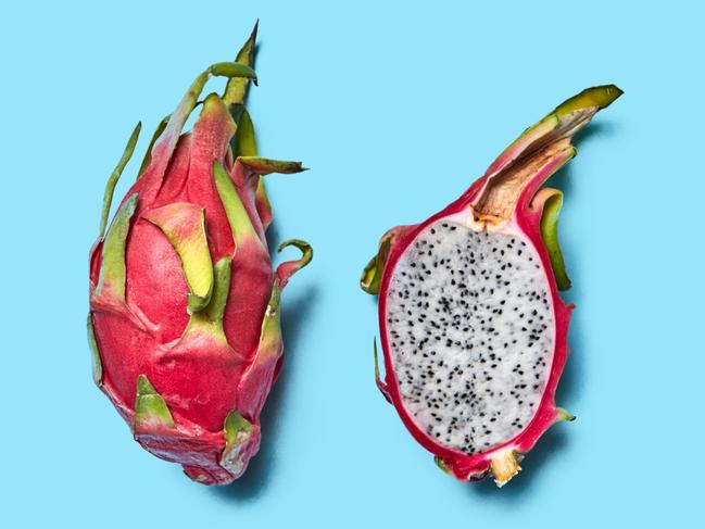 EMBARGO FOR TWAM, 25 JANUARY 2025. FEE MAY APPLY. Ripe whole and juicy half fruit of pitahaya on a blue background with space for text. Flat lay