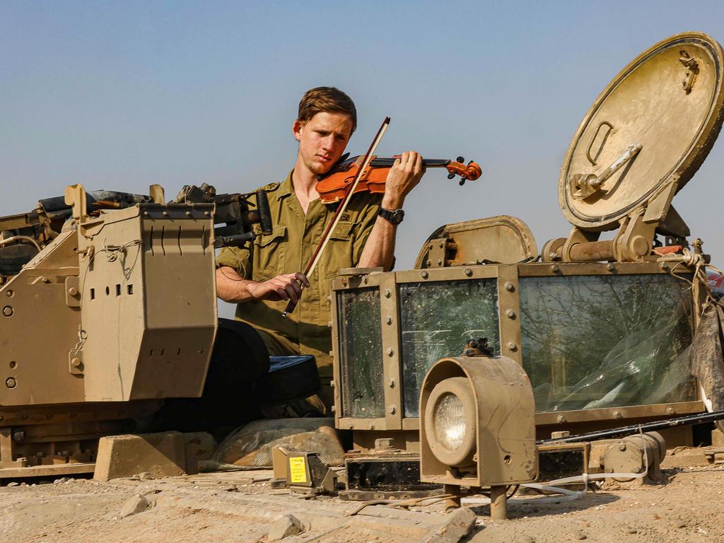 An Israeli soldier plays a violin whilst resting in a tank, amid continuing battles in Gaza. Picture: Menahem Kahana/AFP