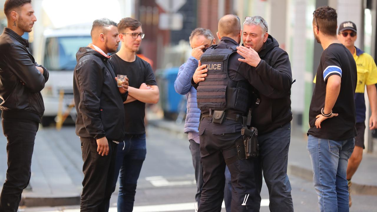 Sisto Malaspina’s loved ones embrace a police officer outside the restaurant. Picture: Alex Coppel