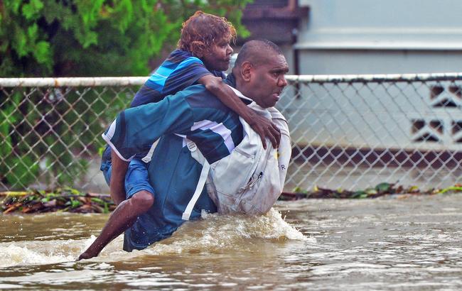 Leslie Noble carries his aunty Clara Fullerton across floodwaters on the corner of Norris Street and Queens Road. Picture: Zak Simmonds