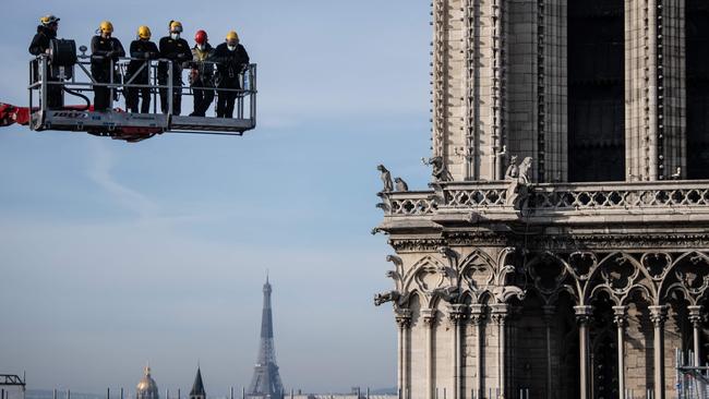 Workers on a crane look at the Notre-Dame Cathedral site on November 24, 2020, in Paris. The cathedral reopened at the weekend, five years after the 2019 fire which ravaged the world heritage landmark and toppled its spire. Picture: Martin Bureau/AFP