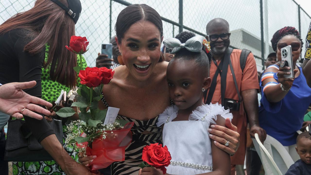 Meghan Markle receives flowers from a girl upon her arrival for an exhibition sitting volleyball match at Nigeria Unconquered in Abuja. Picture: AFP