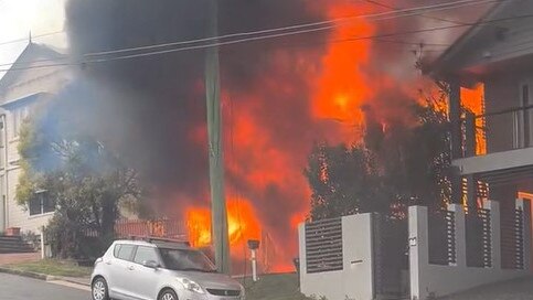 Fire crews are battling multiple house fires in an up-market Brisbane street in the inner north after a blaze spread to neighbouring homes.