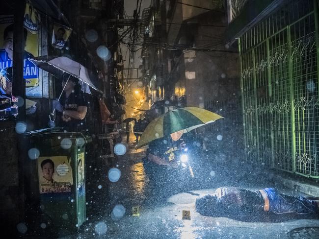 First Prize, Stories © Daniel Berehulak, for The New York Times Title: They Are Slaughtering Us Like Animals Heavy rain pours as police operatives investigate inside an alley where a victim, Romeo Joel Torres Fontanilla (37) was killed by two unidentified gunmen riding motorcycles in the early morning in Manila, Philippines.Beyond those killed in official drug operations, the Philippine National Police have counted more than 3,500 unsolved homicides since 1 July. The victims, suspected users and pushers, are not afforded any semblance of due process.