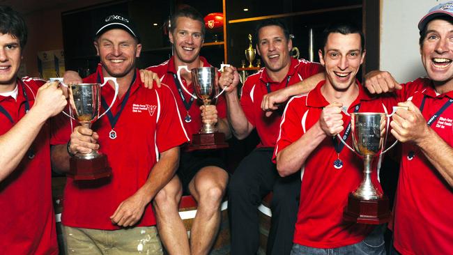 Scott Tregoning and coach Michael Scott (rear) celebrate a premiership triple (senior, reserves, under-18s) at Olinda.