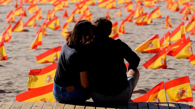 A couple sit next to thousands of Spanish flags, representing the Spanish victims of COVID-19, on Patacona beach in Valencia. Picture: AFP