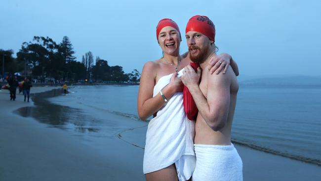 Samantha Hawker and Chris McGrath from New South Wales warm up with a hot water bottle after the swim. Dark Mofo Winter solstice nude swim. Picture: NIKKI DAVIS-JONES