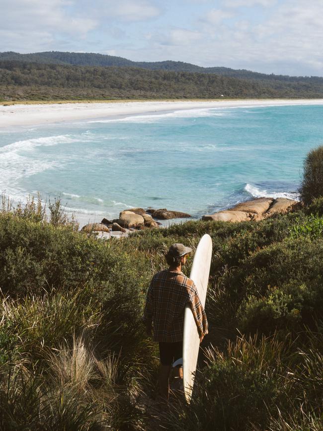 A surfer at Bay of Fires, Tasmania. Picture: Wish You Were Here Aus