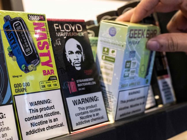 A woman grabs a nicotine product at a vaping and consumption supply store in San Jose on May 14, 2024. Costa Rican authorities announced Tuesday that they will "ban products containing synthetic nicotine" in the country, targeting the substance used in packaging for smoking in vapes and electronic cigarettes. (Photo by Ezequiel BECERRA / AFP)