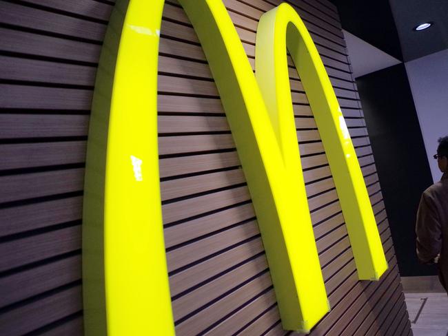 FILE - In this Dec. 17, 2014 file photo, a man walks by a McDonald's logo in front of its restaurant in Tokyo. McDonald’s is set to unveil its latest plans to revive its sputtering business on Monday, May 4, 2015. (AP Photo/Eugene Hoshiko, File)