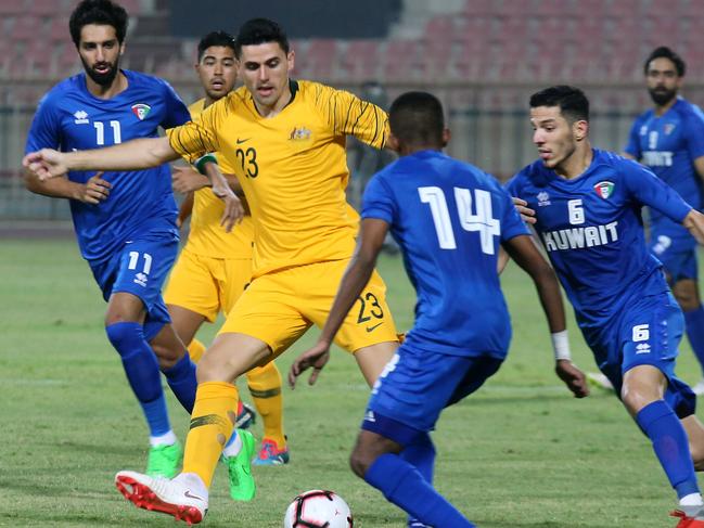 Australia's Tom Rogic kicks the ball past Kuwait's Dhari Saed (C) and Sultan al-Enizi during a friendly football match between Kuwait and Australia at the Kuwait Sports Club Stadium in Kuwait City on October 15, 2018. (Photo by Yasser Al-Zayyat / AFP)