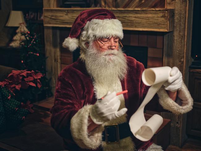 Santa Claus in a home, reading a Christmas list. istock image