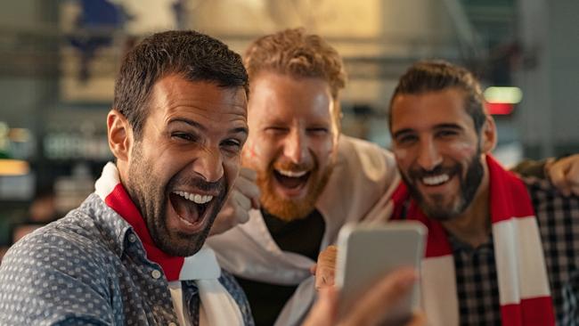 Excited men watching football in streaming on smartphone winning an online bet; generic gambling betting