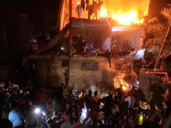 People watch and search for victims amid the rubble of a smouldering building, following an Israeli strike in Rafah in the southern Gaza Strip. Picture: AFP