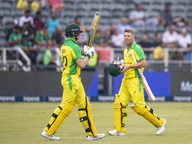 David Warner, right, leaves the field as teammate Steven Smith strides to the crease. Picture: AP Photo/Themba Hadebe