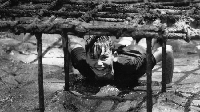 Patrick Ballesty, 12, of NSW, slithers through the Challenge Hill commando obstacle course at the 15th Australian Scouts Jamboree at Woodhouse in 1988.