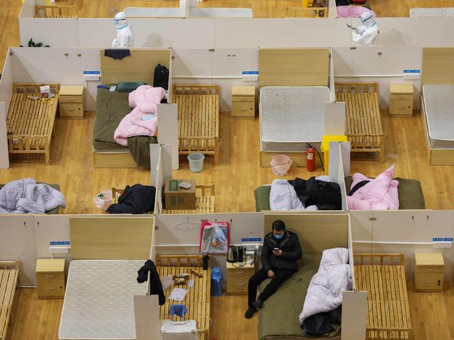 A medical worker (top left) walking past empty beds as a patient rests at a temporary hospital set up for COVID-19 in a sports stadium in Wuhan, in China. Picture: STR/AFP