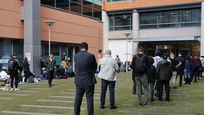 People wait in two lines, one for passport inquiries and one for passport collection. The lines are indistinguishable. Picture: Tim Hunter.