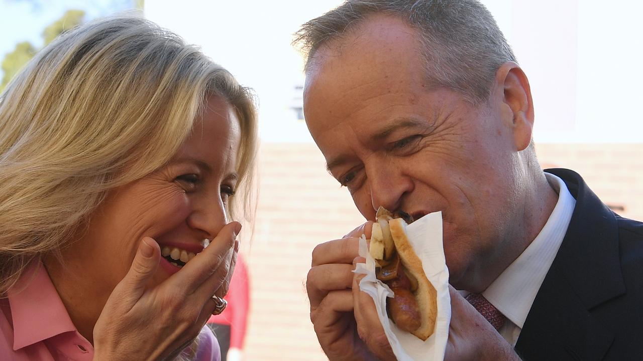 Labor politician Bill Shorten tucks into a democracy sausage, watched on by wife Chloe, on federal election day in 2019. Picture: AAP Image
