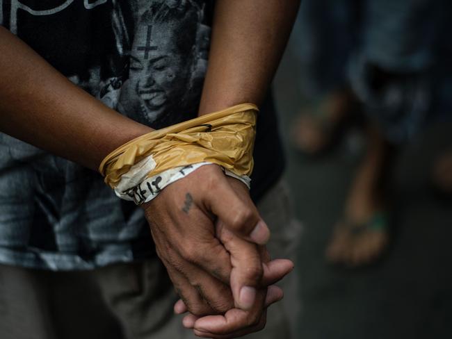 TOPSHOT - A man is seen with his hands bound as male residents are rounded up for verification after police officers conducted a large scale anti-drug raid at a slum community in Manila on July 20, 2017.  One resident was killed in the raid according to police. President Rodrigo Duterte swept to an election victory last year largely on a pledge to wipe out his nation's illegal drugs trade within three to six months, saying he would do so by killing thousands of people. Duterte fulfilled his vow on the death toll, drawing condemnation from rights groups who warned he may be orchestrating a crime against humanity as police and unknown assassins filled slums with bullet-ridden corpses. / AFP PHOTO / NOEL CELIS