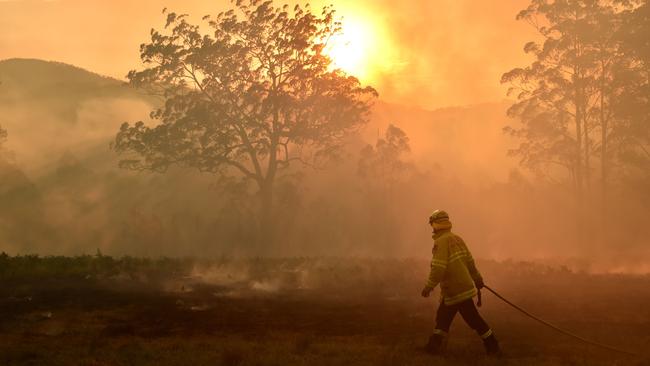 A firefighter defends a property from a bushfire near Taree, in NSW. Picture: AFP