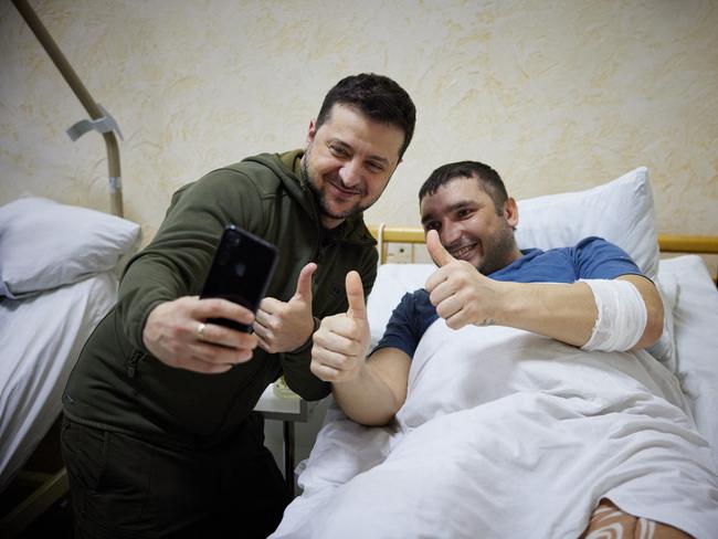 Ukrainian President Volodymyr Zelensky snaps a selfie with an injured man laying on a bed during a visit at a military hospital in Kyiv. Picture: AFP.