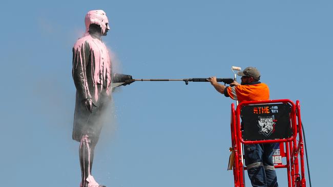 A worker cleans a statue of Captain Cook after it was vandalised in Melbourne in 2018. Picture: David Crosling/AAP