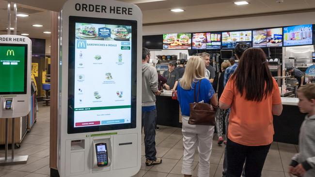 Customers queue inside a McDonalds restaurant ignoring new self-service kiosks. Stratford upon Avon in England.