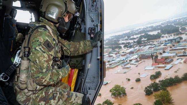 A handout photo taken on February 28 and released on March 3, 2022 shows Australian Army aircrewman Sergeant Rick Scott from the School of Army Aviation surveying flood waters from an MRH-90 Taipan helicopter over the northern New South Wales city of Lismore during Operation Flood Assist 2022. (Photo by Bradley RICHARDSON / Australian Defence Force / AFP) / ----EDITORS NOTE ----RESTRICTED TO EDITORIAL USE MANDATORY CREDIT " AFP PHOTO / AUSTRALIAN DEFENCE FORCE" NO MARKETING NO ADVERTISING CAMPAIGNS - DISTRIBUTED AS A SERVICE TO CLIENTS