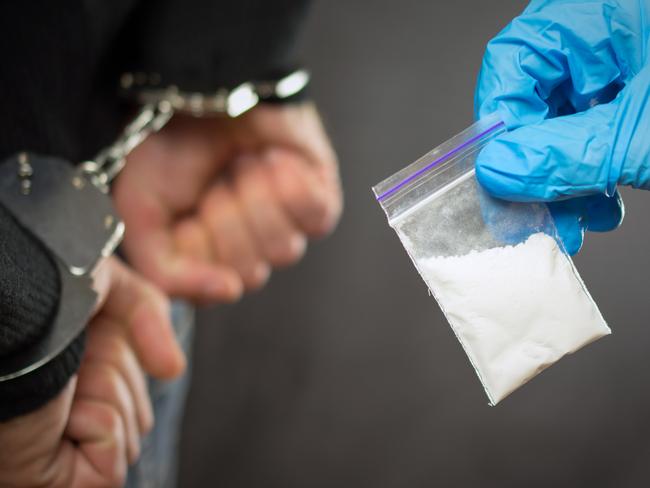 A police officer finds drugs during the search of drug dealers istock image