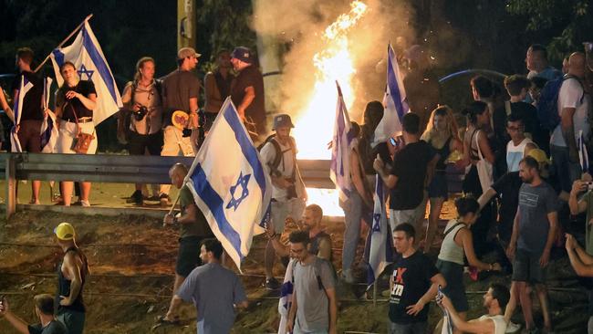 Demonstrators gather around a bonfire as they block a highway during a protest against the Israeli government's judicial reform plan in Tel Aviv.