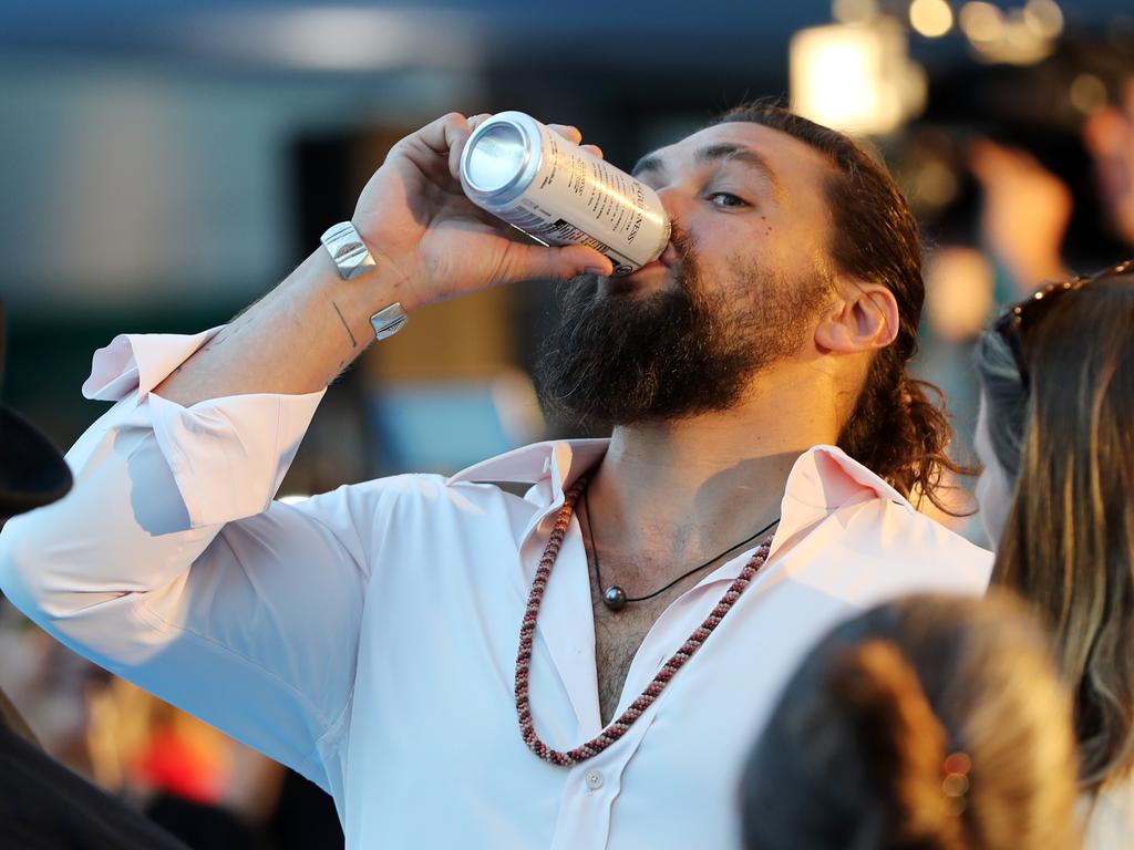 Jason Momoa downs a beer at the Australian premiere of Aquaman. Picture: Nigel Hallett