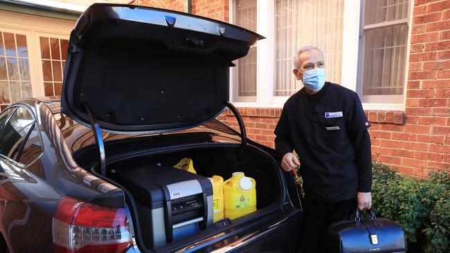 Jamal Rifi loads a fridge filled with vaccines into his car at Belmore Medical Centre. Picture: John Feder