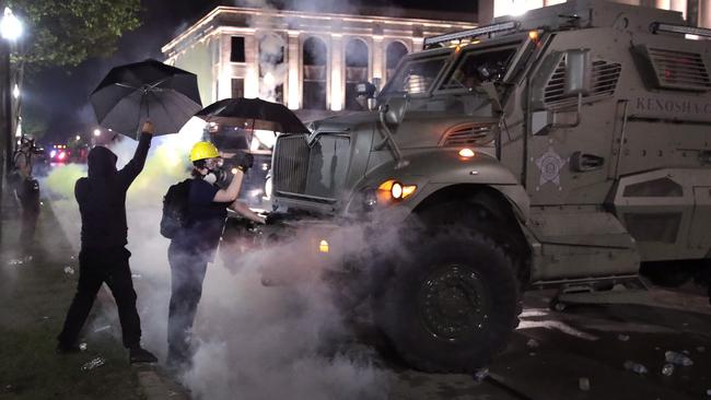 As tear gas fills the air, demonstrators confront police in front of the Kenosha County Courthouse in Kenosha, Wisconsin, on Wednesday (AEST). Picture: AFP