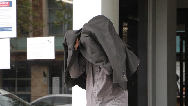 Anthony Lesley Jones leaves Wyong Local Court with his face covered after being charged with stealing pieces of artwork belonging to the family of Patrick Carroll. Picture: Fiona Killman