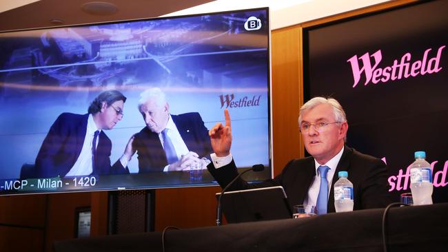 Peter and Sir Frank Lowy (both on a screen) and Steven Lowy announce the takeover.