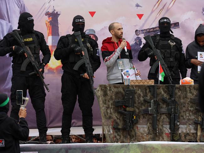 TOPSHOT - Israeli hostages Avera Mengistu (R) and Tal Shoham (3rd-L) are flanked by Palestinian Hamas fighters as they stand on a stage during their release in Rafah in the southern Gaza Strip on February 22, 2025. Masked militants paraded Tal Shoham and Avera Mengistu on stage in the southern Gazan city of Rafah before handing them over to officials from the Red Cross. (Photo by Omar AL-QATTAA / AFP)